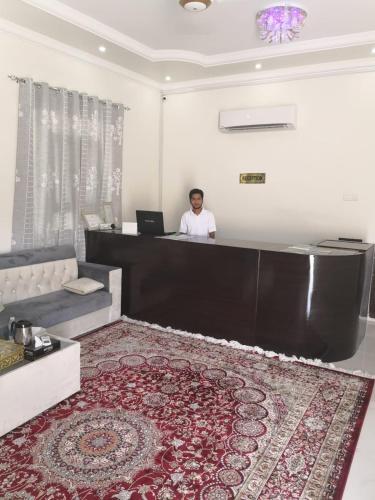 a man sitting at a reception desk in a room at Ras Al Jinz Turtle Guest House in Junayz al Janūbī