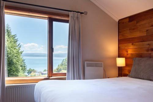 a bedroom with a bed and a large window at Hotel y Cabañas El Parque in Villarrica