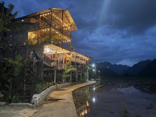 a building with lights on it next to a river at Pac Ngoi Village Homestay in Ba Be