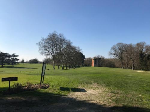 une vue d'un terrain de golf avec un château au loin dans l'établissement Manoir de l'Herbier, à Saint-Sulpice