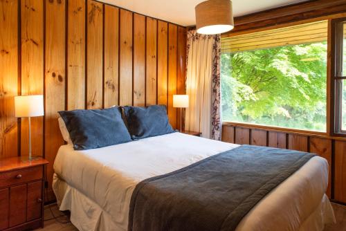 a bedroom with a bed and a large window at Hotel y Cabañas El Parque in Villarrica