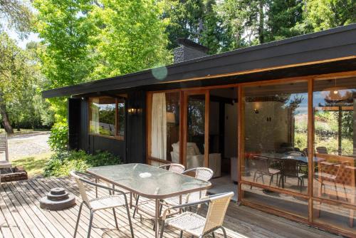 a house with a table and chairs on a deck at Hotel y Cabañas El Parque in Villarrica