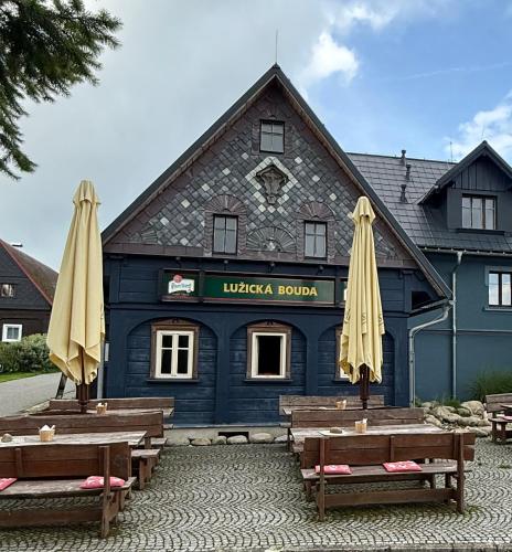a blue building with two umbrellas in front of it at Lužická bouda - penzion & hospůdka in Mařenice