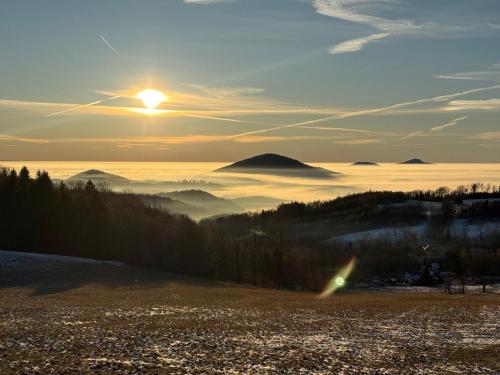 a view of the sun rising over a field with a mountain at Lužická bouda - penzion & hospůdka in Mařenice