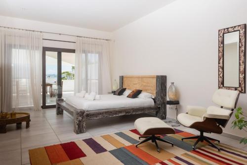 a bedroom with a bed and two chairs and a mirror at Luxury Villa with Outdoor Bar, Ibiza Villa 1027 in Talamanca