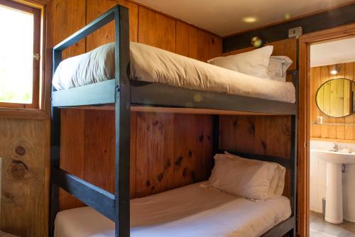 two bunk beds in a room with a sink at Hotel y Cabañas El Parque in Villarrica