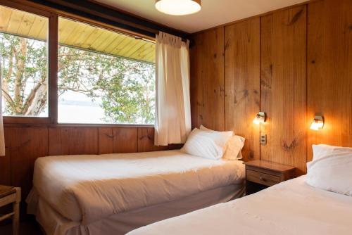 two beds in a room with a window at Hotel y Cabañas El Parque in Villarrica