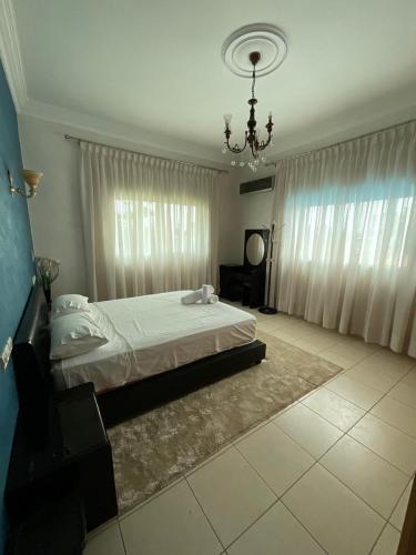 a bedroom with a large bed and a chandelier at Villa Royale Prestige Safaa in Dar Bouazza