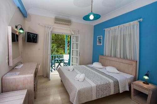 a bedroom with a bed with blue walls and a balcony at Hotel Andreas in Kamari