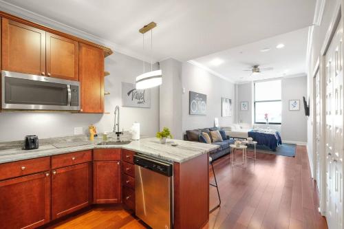 a kitchen with wooden cabinets and a living room at XL Studio - Stylish Studio with Rooftop Pool in Philadelphia