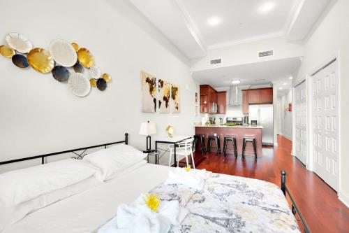 a white bedroom with a large bed and a kitchen at XL Studio - Premier Studio with Gym Access in Philadelphia