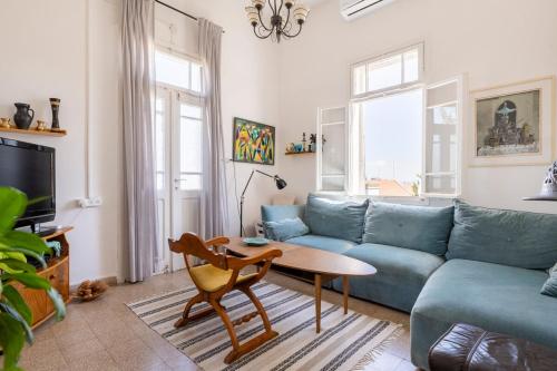 a living room with a blue couch and a table at Charming 2 BR Apt By The Foot Of The Bahai Temple in Haifa