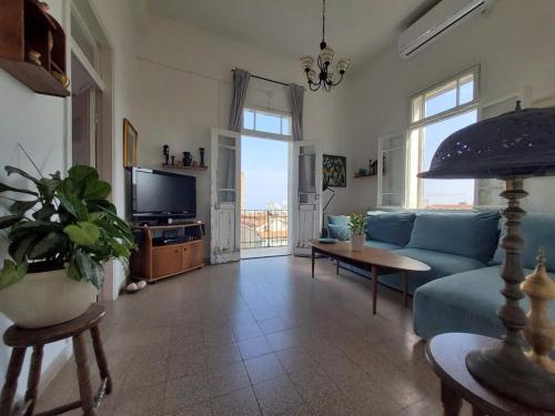 a living room with a blue couch and a tv at Charming 2 BR Apt By The Foot Of The Bahai Temple in Haifa