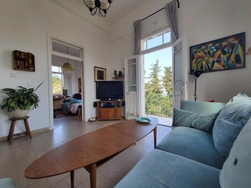 a living room with a blue couch and a table at Charming 2 BR Apt By The Foot Of The Bahai Temple in Haifa
