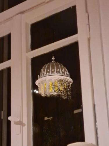 a chandelier is seen through a window at Charming 2 BR Apt By The Foot Of The Bahai Temple in Haifa