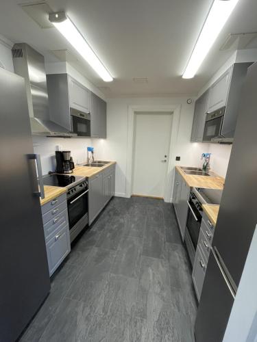 a large kitchen with white cabinets and stainless steel appliances at Vandrarhemmet Åmål in Åmål