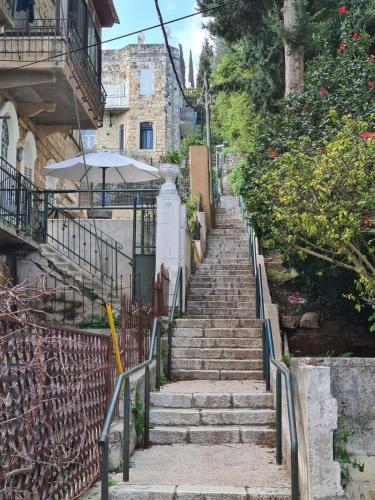 a set of stairs leading up to a building with an umbrella at Charming 2 BR Apt By The Foot Of The Bahai Temple in Haifa