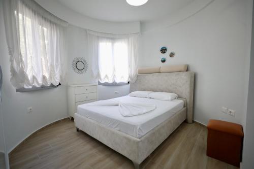 biała sypialnia z łóżkiem i dwoma oknami w obiekcie Neta's Apartment w Sarandzie