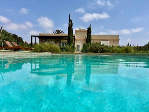 una gran piscina de agua azul frente a una casa en Villa moderne avec Piscine privée à 30 mins d'Agadir, en Sidi Bibi