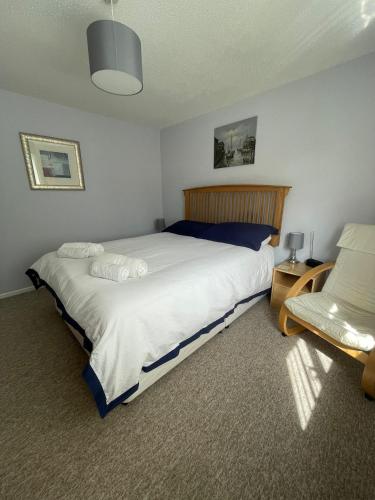 a bedroom with a large bed and a chair at Sunny detached bungalow, Nr Looe in Saint Keyne
