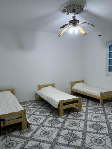 a room with two beds and a ceiling fan at MAHDIA REJICHE MAISON AVEC PISCINE privee in Rejiche