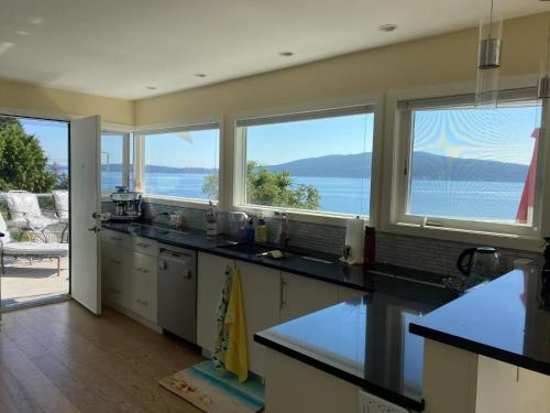 a kitchen with windows and a view of the water at Beachbreeze Panoramic Oceanview 4BR 3BA Romantic Sunrise & Celestial Views in Mill Bay