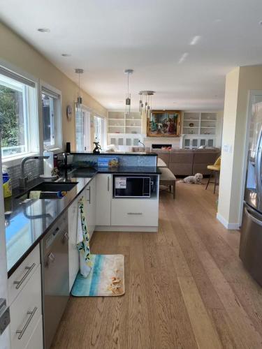 a kitchen with white counters and a living room at Beachbreeze Panoramic Oceanview 4BR 3BA Romantic Sunrise & Celestial Views in Mill Bay