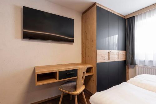 a bedroom with a desk with a tv and a bed at ALPENAPART LADIS ehemals Alpenapart Alexander in Ladis