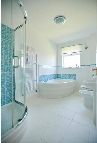 a white bathroom with a tub and a sink at Sunrise in Saint Columb Major