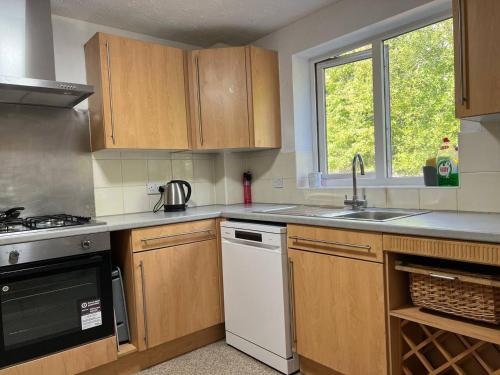 a kitchen with wooden cabinets and a white dishwasher at Etruria House - Near Water World, Festival Park and Bet365 in Stoke on Trent