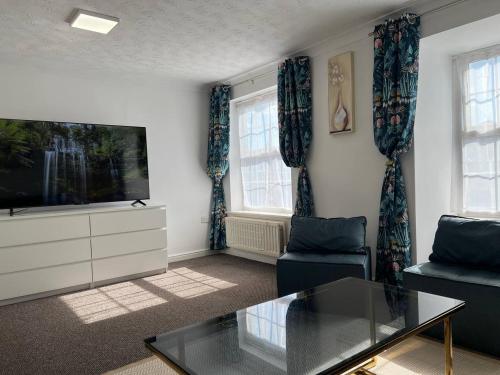 a living room with a flat screen tv and two windows at Etruria House - Near Water World, Festival Park and Bet365 in Stoke on Trent