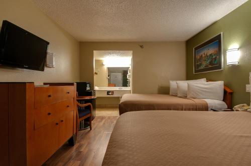a hotel room with two beds and a flat screen tv at Vagabond Inn Bakersfield South in Bakersfield