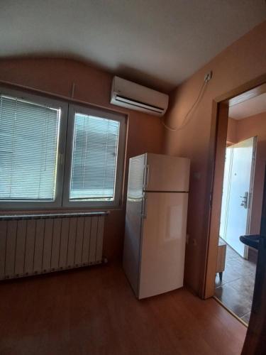biała lodówka w pokoju z dwoma oknami w obiekcie Pafi Apartment w mieście Skopje