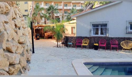 a patio with chairs and a swimming pool next to a building at Oasis rural in Benidorm in Benidorm