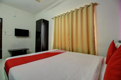 a bedroom with a red and white bed and a window at Hotel O Manu Residency in Bengaluru