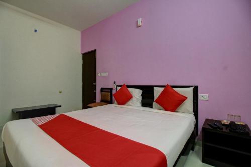 a bedroom with a large bed with red pillows at Hotel O Manu Residency in Bengaluru