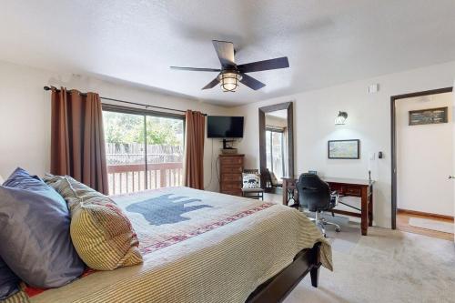 1 dormitorio con 1 cama, ventilador de techo y escritorio en Lazy Bear Cabin ~ Dog-friendly home with private hot tub, ping-pong, basketball & firepit, en Big Bear Lake
