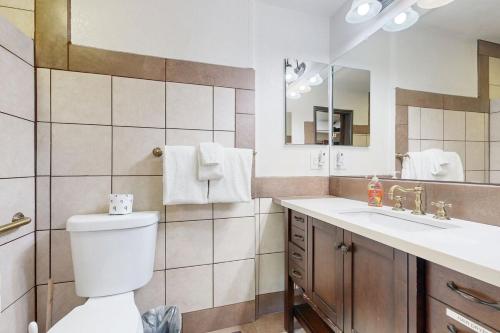 Un baño con inodoro, lavabo y espejo. en Lazy Bear Cabin ~ Dog-friendly home with private hot tub, ping-pong, basketball & firepit, en Big Bear Lake