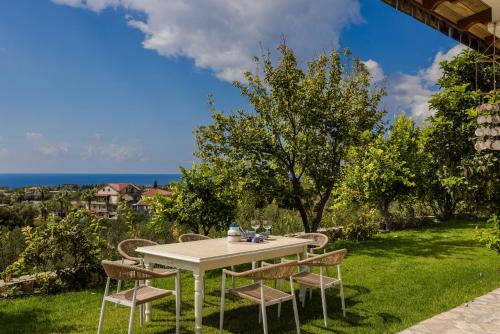 a table and chairs on a lawn with the ocean at Pantheon Villa Svoronata in Svoronata