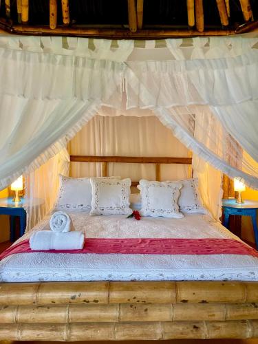 a bedroom with a canopy bed with white sheets and pillows at Minca Ecohabs Hotel in Minca
