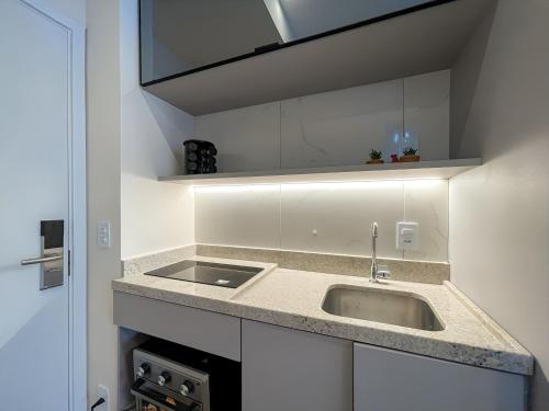 eine Küche mit Spüle und weißen Schränken in der Unterkunft Handy Paraíso condomínio com piscina ao lado do Ibirapuera in São Paulo