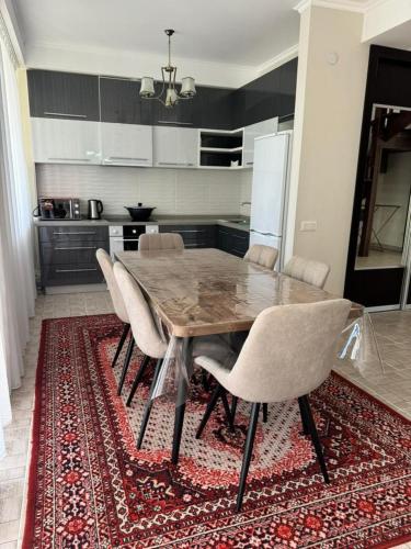 a kitchen with a wooden table and chairs on a rug at Baytur-Yilla09 in Bosteri