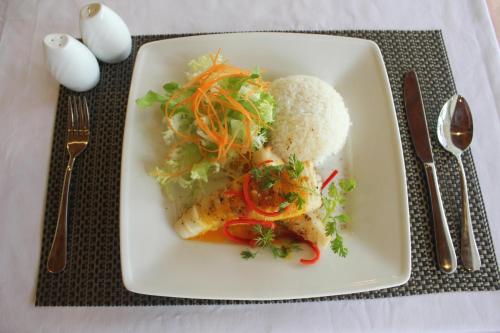 a plate of food with fish and vegetables on a table at Bamboo Hotel Phu Quoc in Phu Quoc