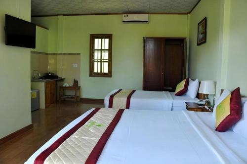 a hotel room with two beds and a television at Bamboo Hotel Phu Quoc in Phu Quoc