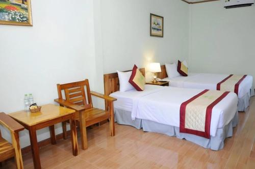 two beds in a room with a table and a desk at Bamboo Hotel Phu Quoc in Phu Quoc