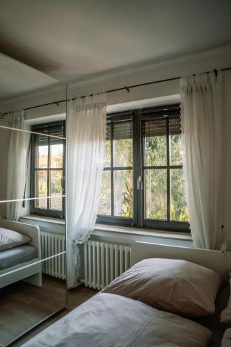 a bedroom with white curtains and a bed and a mirror at Casa pasa - Idylle mit Bergblick in Inzell
