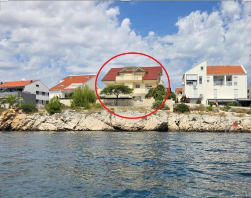 a red circle in the water in front of houses at Luxury Beachfront Villa Bregeš - First row to the sea in Povljana