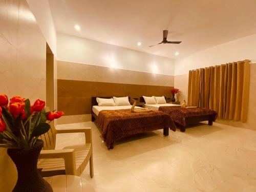 1 dormitorio con 2 camas y un jarrón de flores rojas en RR Holiday Grand, en Kodaikanal
