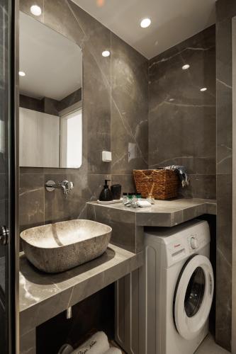 a bathroom with a sink and a washing machine at CasaNova Luxury Apartment in Naxos Chora