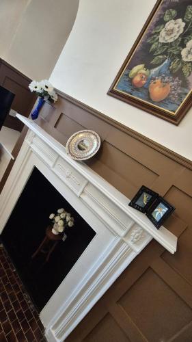 a room with a fireplace with a painting and flowers on it at Beautiful 4BR Georgian house in Wisbech
